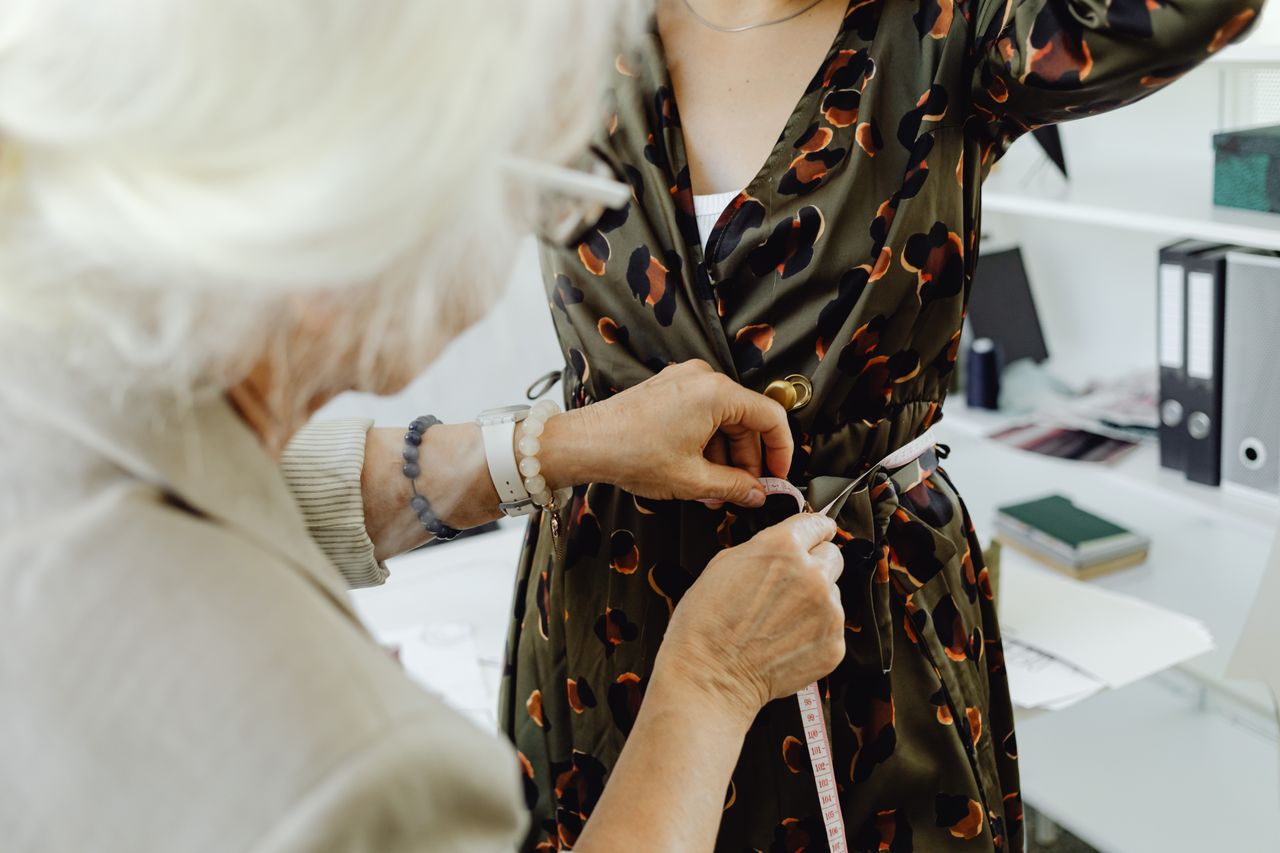 Crafting Captivating Headlines: Your awesome post title goes here An elderly seamstress measures a woman's waist for a custom dress fitting.