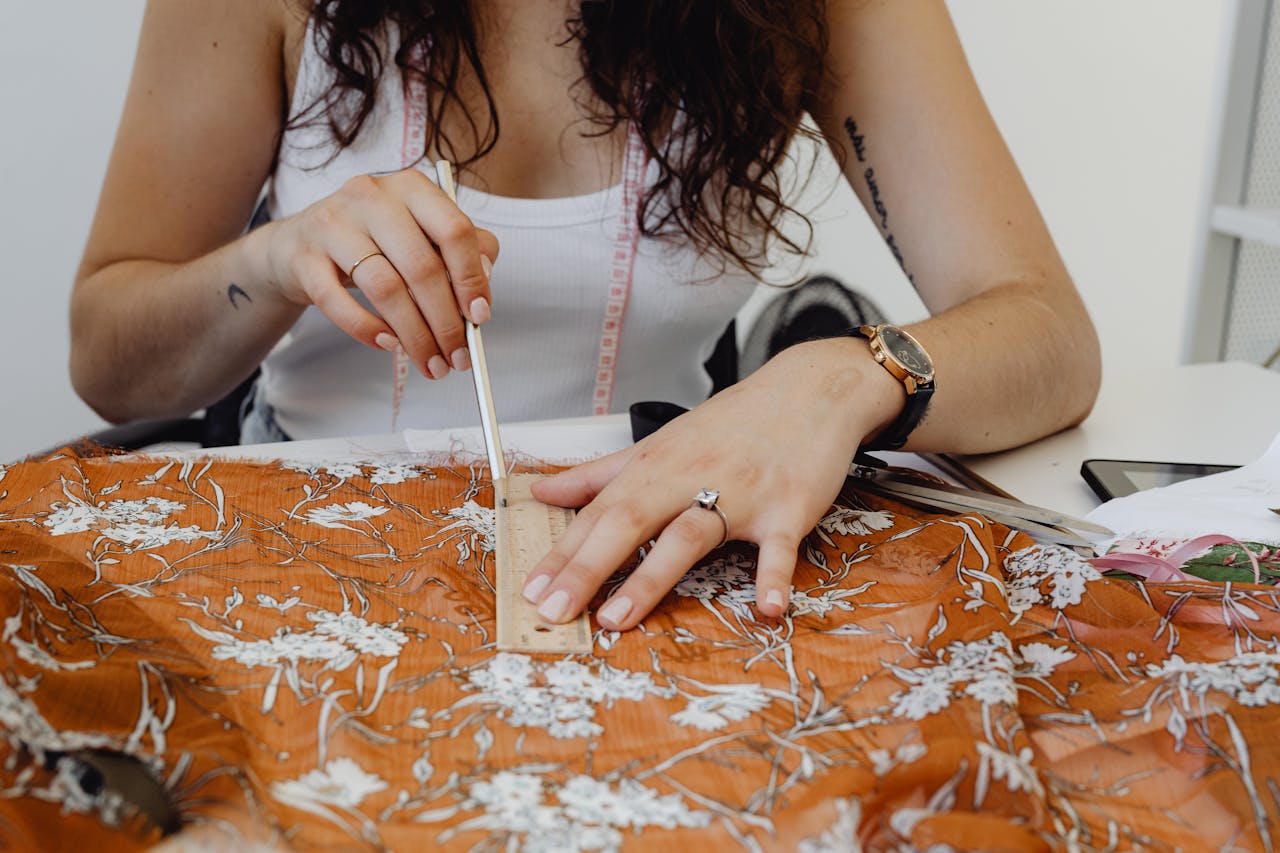 The Art of Drawing Readers In: Your attractive post title goes here Close-up of a designer measuring fabric with a ruler and pencil on a worktable.